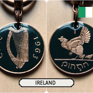 May include: A copper-colored keychain featuring two sides of an Irish coin. One side shows a harp and the year 1963, the other a hen with chicks and the word "Pingin". The coin has a dark green enamel background.