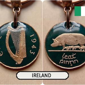 May include: A copper-coloured keychain pendant showing two sides of an Irish coin. One side features a harp and the year 1943, the other a pig with piglets. The pendant has a green enamel background and the word "Ireland" is written below.