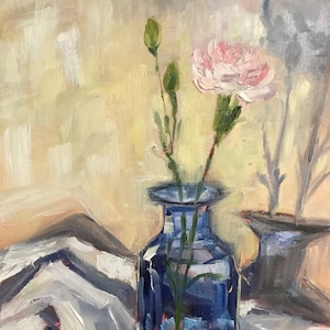 May include: An oil painting depicts a blue glass vase holding a pink carnation and green buds. The vase sits on a white and gray striped cloth. The background is a soft yellow and peach color. The artist's signature, Bignell, is in the lower right corner.