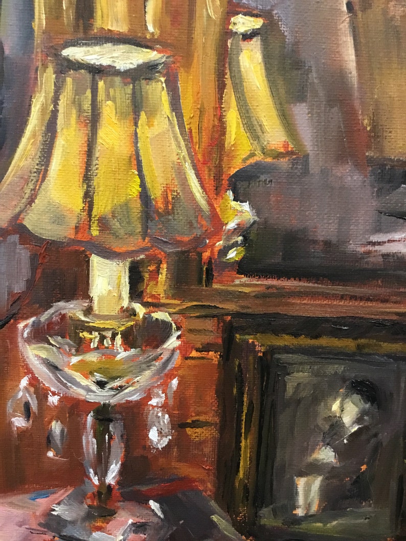 May include: A vintage-style table lamp with a yellow lampshade and a clear glass base with crystal accents. The lamp is sitting on a wooden table next to a framed picture.