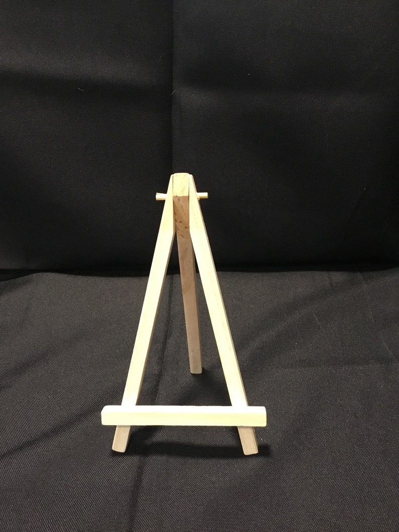 May include: A small wooden easel, perfect for displaying small artwork or photos. The easel is made of natural wood and has a simple, classic design.