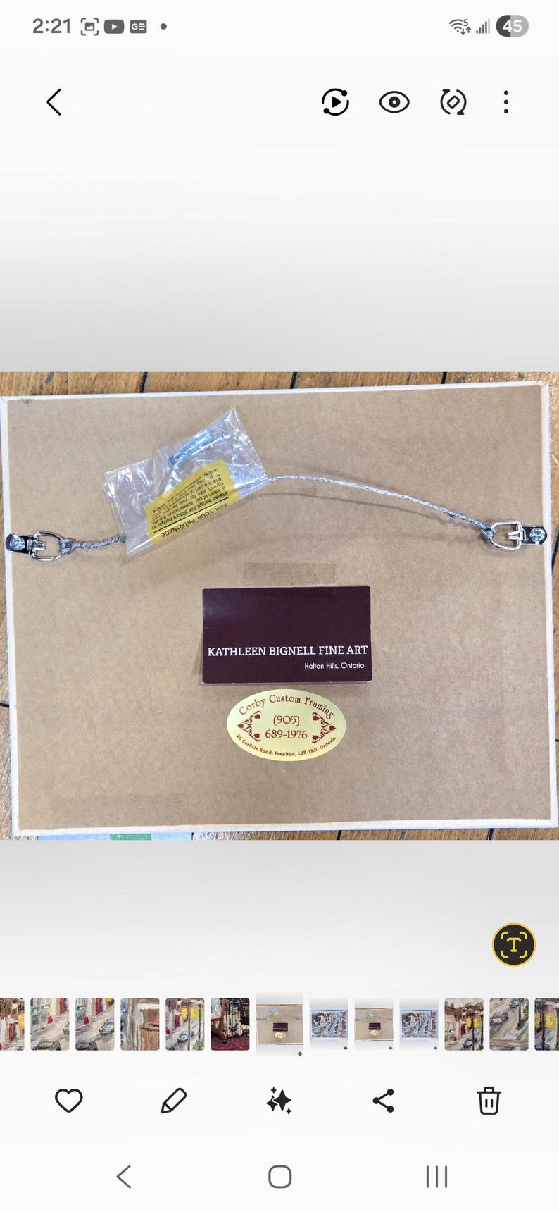 May include: The back of a framed artwork, showing the mounting hardware, wire, and labels. The labels include the artist's name, "Kathleen Bignell Fine Art," and the framer's information, "Corby Custom Framing."