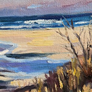 May include: A painting of a seascape with a sandy beach, blue water, and a cloudy sky. The painting is done in a loose, impressionistic style, with visible brushstrokes. The artist's signature, "Ruggell", is visible in the lower right corner.
