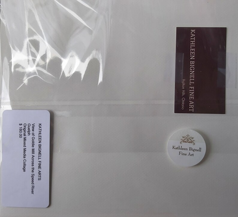 May include: A mixed media collage by Kathleen Bignell, titled "View of Goldie Mill Across the Speed River." The artwork is packaged in a clear plastic sleeve. The image includes a business card and a round sticker with the artist's name.