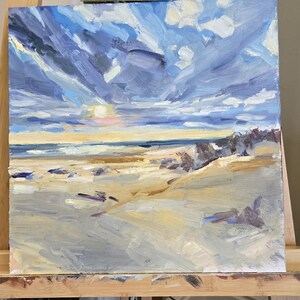 May include: An oil painting on a square canvas depicting a coastal landscape with a sandy beach in the foreground, a dark blue ocean horizon, and a dramatic sky filled with thick, textured brushstrokes of blue, white, and yellow clouds.