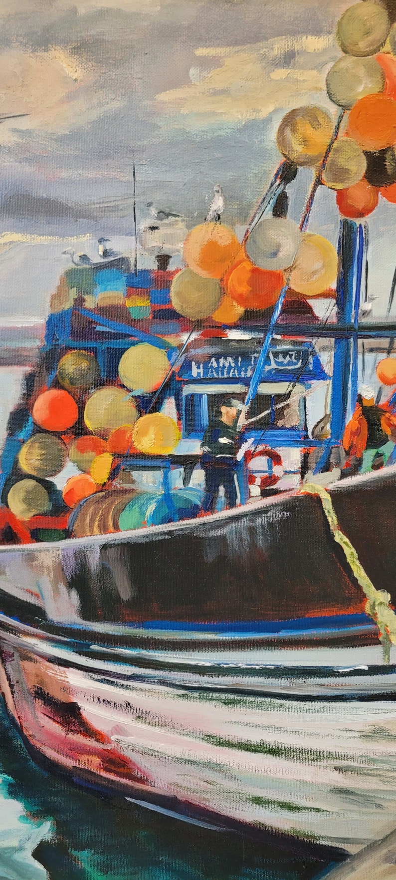 Op de afbeelding: Olieverfschilderij van een vissersboot op zee. De boot is zwart met blauwe en witte accenten en is versierd met oranje en gele boeien. De lucht is bewolkt met tinten grijs en blauw. Het schilderij heeft een textuur, impressionistische stijl.