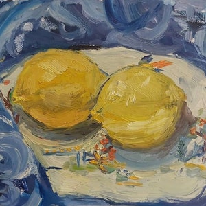 May include: Two yellow lemons on a white plate with a blue and white floral design. The plate is on top of a blue fabric.