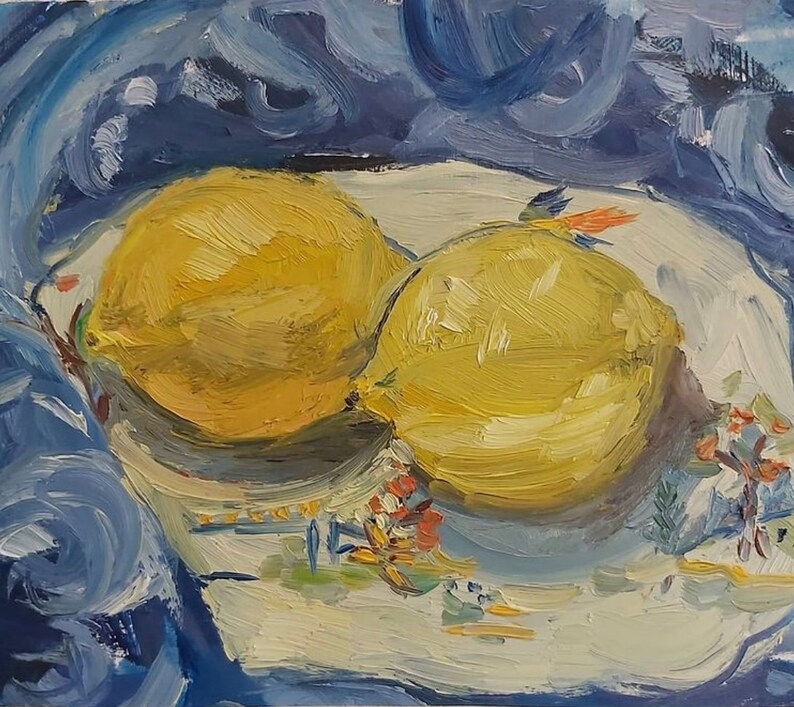 May include: Two yellow lemons on a white plate with a blue and white floral design. The plate is on top of a blue fabric.