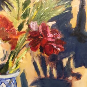 May include: A close-up of a bouquet of red, orange, and pink flowers in a blue and white vase. The flowers are arranged in a vase with a geometric pattern. The background is a blurred image of a dark blue wall.