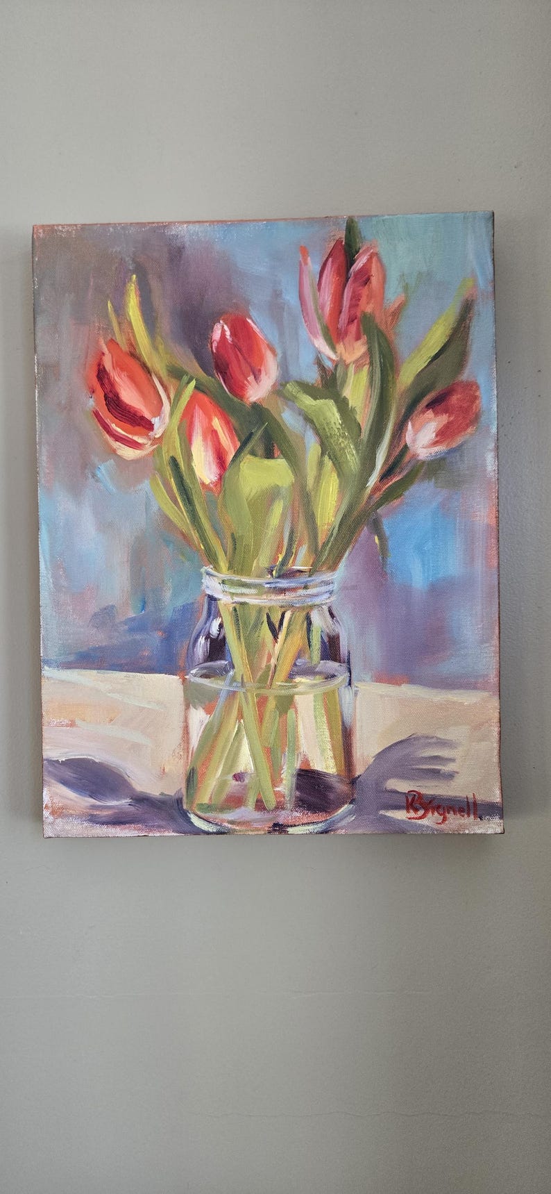 Puede incluir: Pintura al &oacute;leo de tulipanes rojos en un tarro de cristal transparente. Las flores tienen tallos y hojas verdes. El fondo es una mezcla de tonos azules, morados y blancos. La pintura est&aacute; firmada en la esquina inferior derecha.