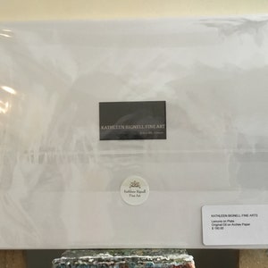 May include: A white envelope with a black label that reads "KATHLEEN BIGNELL FINE ART" and a smaller white label with the text "KATHLEEN BIGNELL FINE ARTS" and the words "Lemons on Plate, Original Oil on Arches Paper, $100.00".