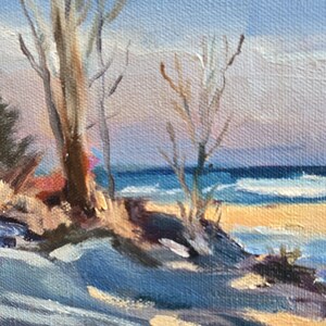 May include: A painting of a winter seascape with a sandy beach, blue water, and bare trees in the foreground. The sky is a light blue with hints of pink and yellow.
