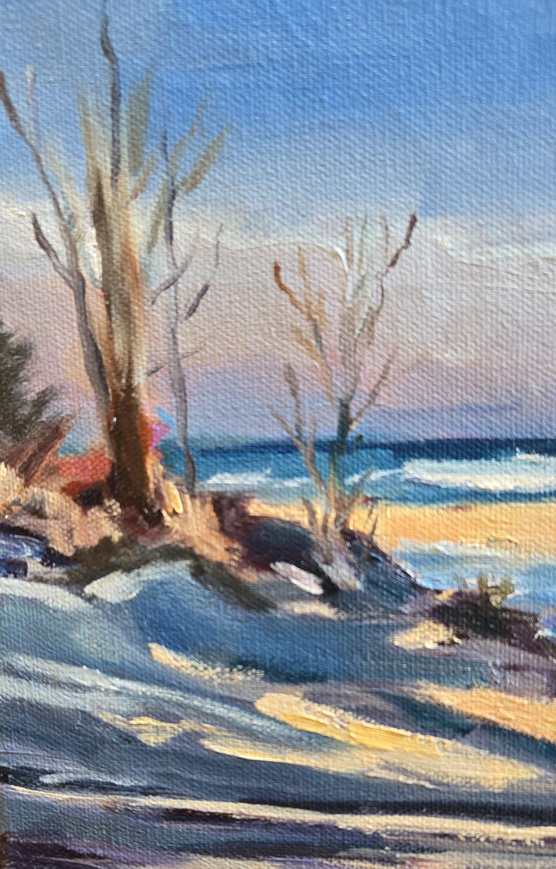 May include: A painting of a winter seascape with a sandy beach, blue water, and bare trees in the foreground. The sky is a light blue with hints of pink and yellow.