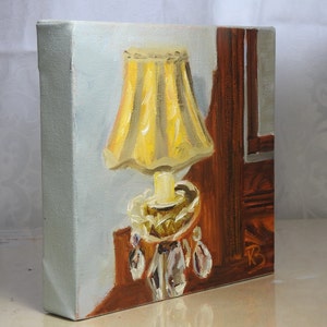 May include: A painting of a yellow lamp with a crystal base and a pleated lampshade. The lamp is on a wooden table next to a dark wood panel.