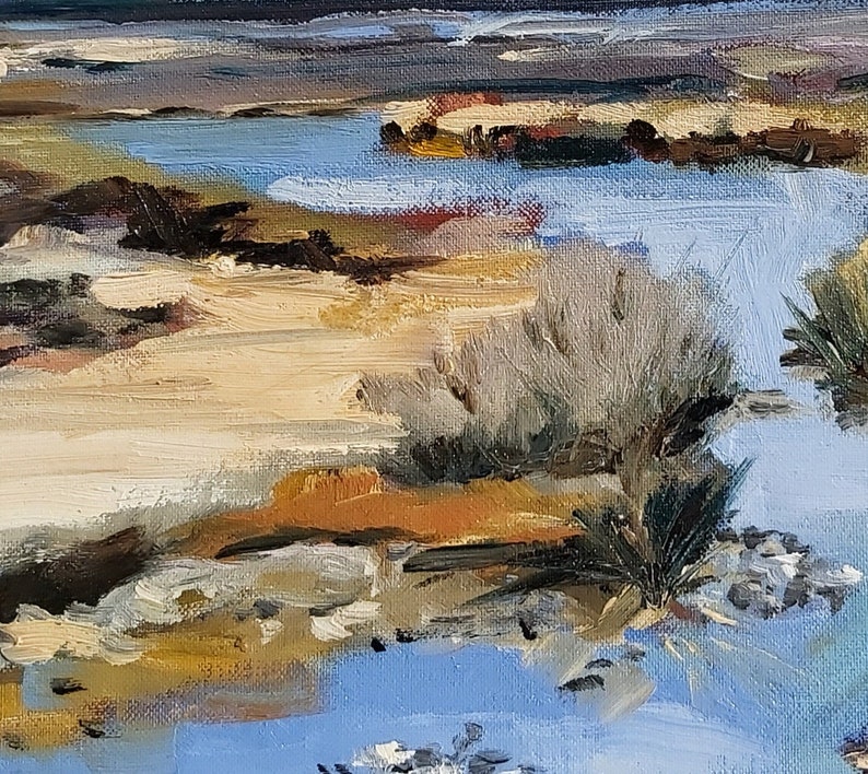 May include: A painting of a landscape with a blue body of water, brown sand, and green bushes. The water is in the foreground and the sand is in the background. The bushes are on the edge of the water.