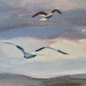 Op de afbeelding: Olieverfschilderij van een kustlandschap met vliegende zeemeeuwen. Het kunstwerk toont een haven met boten en gebouwen onder een bewolkte hemel. Het kleurenpalet omvat tinten blauw, grijs, rood en wit, wat een serene sfeer cre&euml;ert.