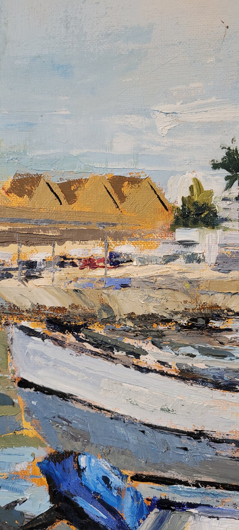 May include: Oil painting of a coastal scene with a boat in the foreground. The boat is painted in shades of blue and white. Buildings with tan roofs are in the background, under a light blue sky.