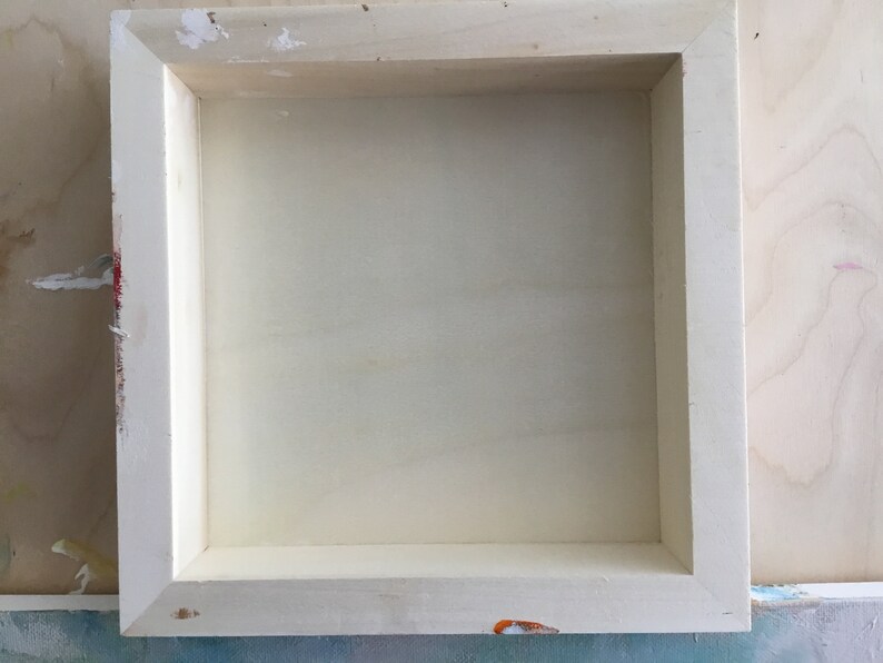 Peut inclure: Un cadre en bois blanc avec un fond blanc. Le cadre est vide et pr&ecirc;t pour une peinture ou une photographie.