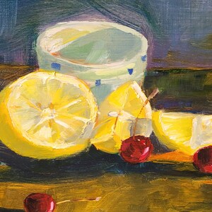 Puede incluir: Pintura al &oacute;leo de un bodeg&oacute;n con medio lim&oacute;n, gajos de lim&oacute;n y cerezas. Una taza azul claro y blanca con lunares azules est&aacute; en el fondo. La pintura tiene una paleta de colores c&aacute;lidos con tonos amarillos, rojos y verdes.