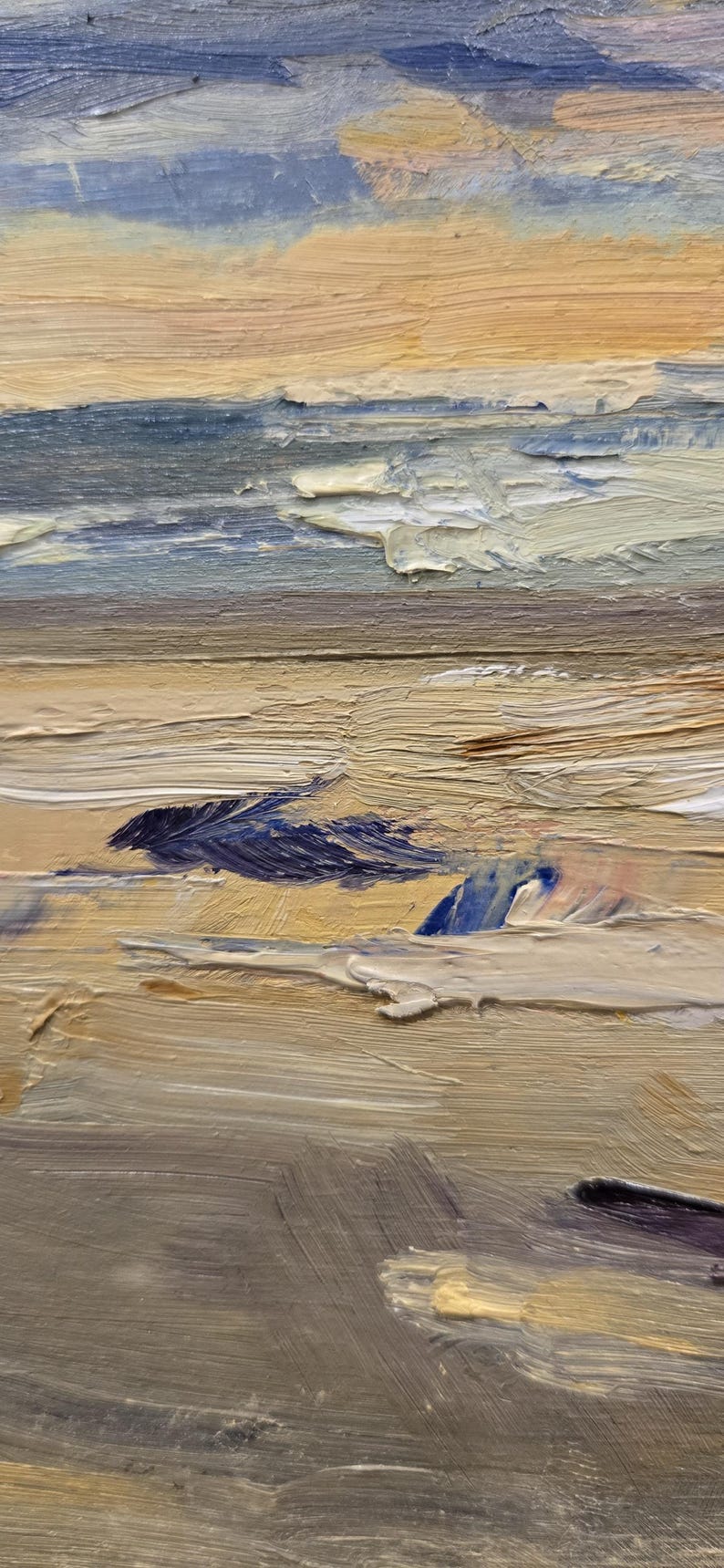 May include: An oil painting on canvas depicting a coastal landscape with thick, textured impasto brushstrokes. The scene features a sandy beach in shades of beige and tan, transitioning into blue ocean waves and a soft, pale yellow and blue sky.