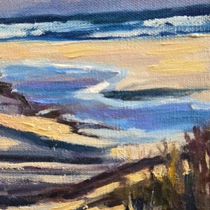 May include: A painting of a beach scene with blue water, yellow sand, and purple and brown hills in the foreground. The sky is a light blue with a pink hue.