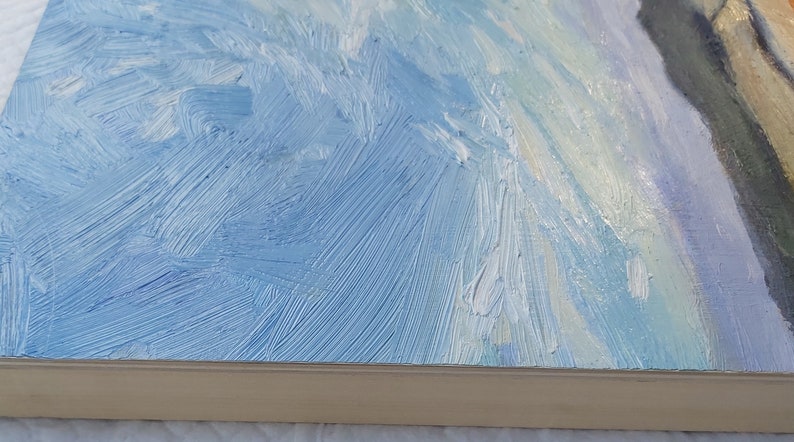 May include: A close-up of a blue and white abstract painting with visible brushstrokes. The painting is framed and the frame is a light wood color.