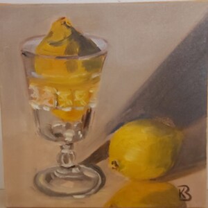 Op de afbeelding: Een olieverfschilderij toont een stilleven met een helder, sierlijk glas gevuld met een citroen. Een andere citroen ligt naast het glas. Het schilderij heeft een warme, neutrale achtergrond en een schaduw.