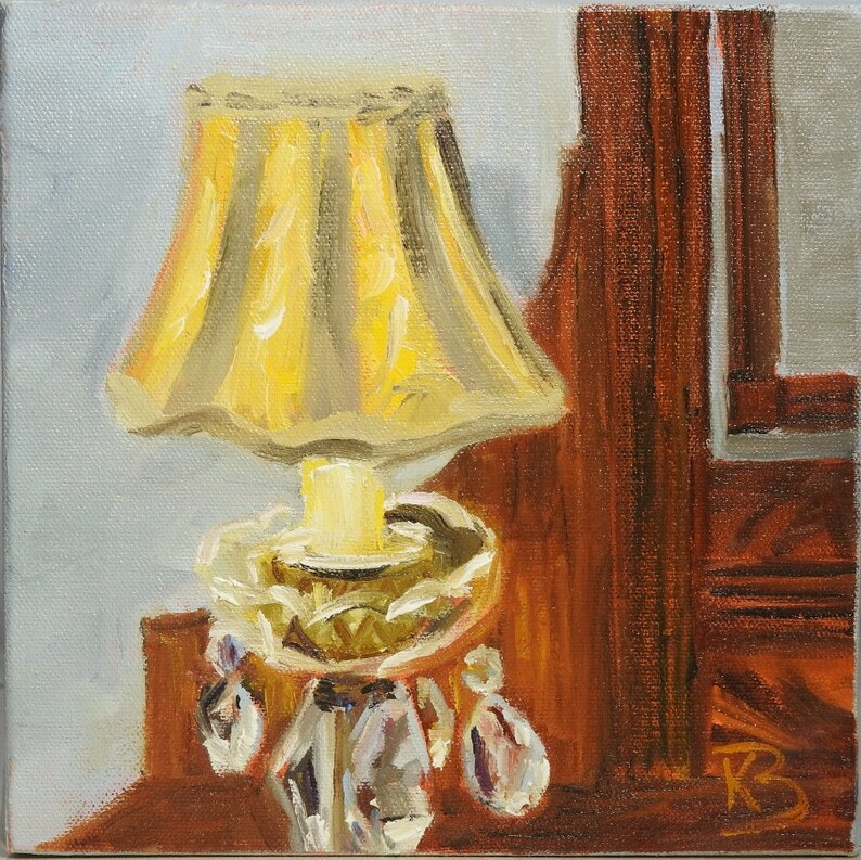May include: A yellow lampshade with a gold base and crystal accents sits on a wooden surface.