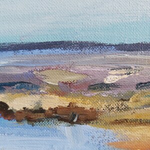 May include: Abstract painting of a landscape with a blue sky, purple mountains, and a brown foreground. The painting is done in a loose, impressionistic style.