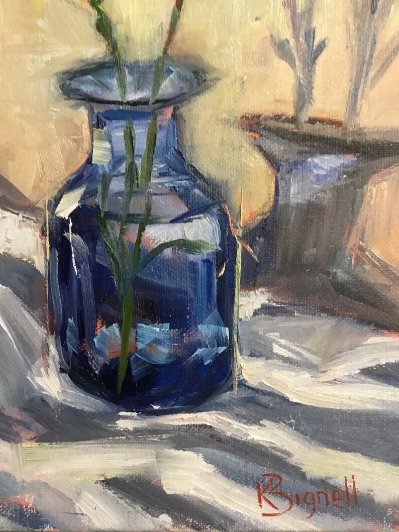 May include: An oil painting depicts a still life with a dark blue glass vase holding green stems. The vase sits on a white and gray striped cloth. A second vase is partially visible in the background. The artist's signature is in the lower right corner.