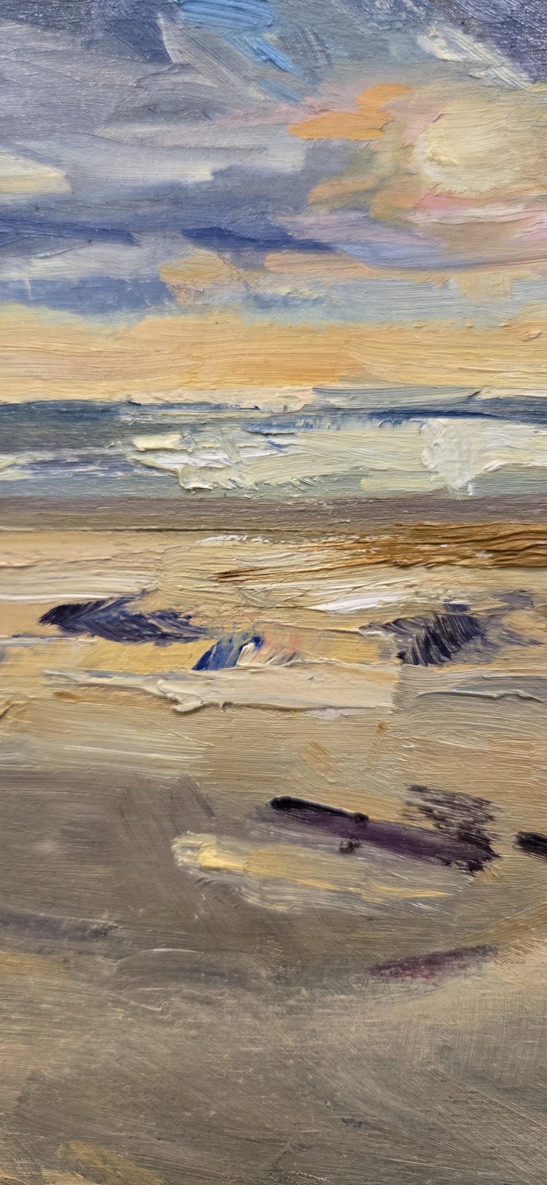May include: An oil painting on canvas depicting a coastal scene with thick, textured brushstrokes. The composition features a sandy beach in the foreground with dark purple shadows, transitioning to blue ocean waves and a soft, cloudy sky in shades of peach.