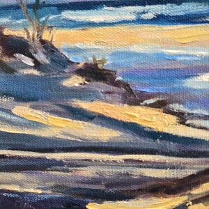 May include: A painting of a beach scene with a lone tree in the foreground. The sky is a pale blue with hints of pink and purple. The water is a deep blue with white waves. The sand is a light yellow. The painting is done in a loose, impressionistic style.