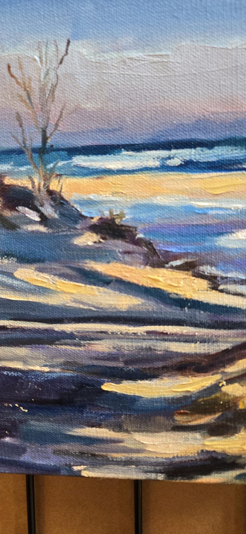 May include: A painting of a beach scene with a lone tree in the foreground. The sky is a pale blue with hints of pink and purple. The water is a deep blue with white waves. The sand is a light yellow. The painting is done in a loose, impressionistic style.