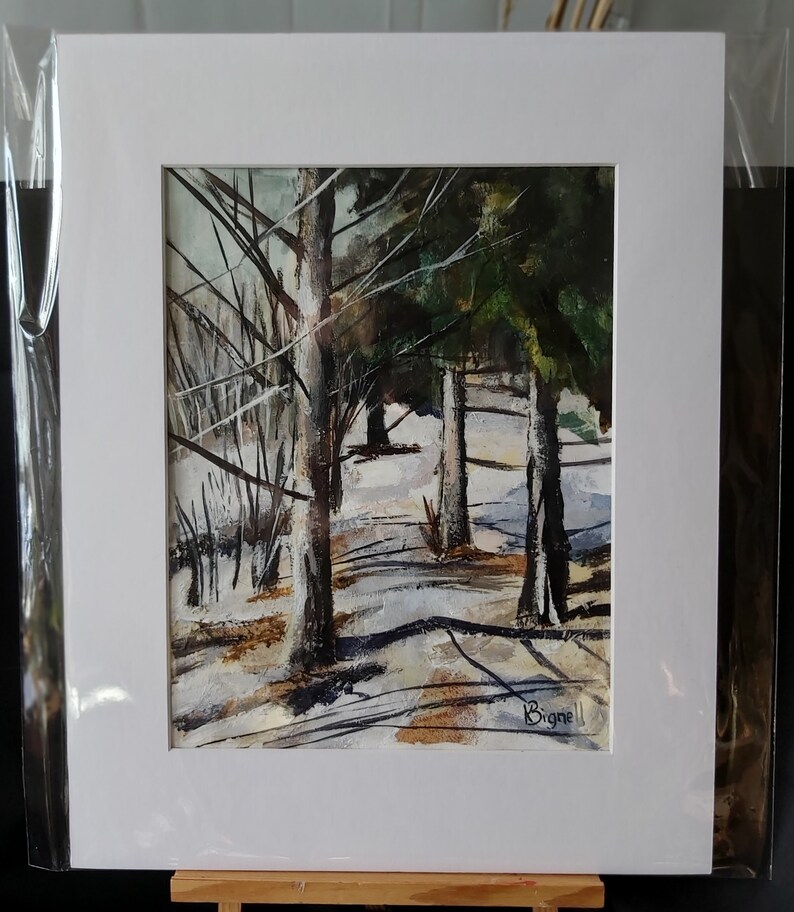 K&ouml;nnte beinhalten: Ein Aquarellbild, das eine verschneite Waldszene mit hohen B&auml;umen und einem hellblauen Himmel zeigt. Das Bild ist in einem wei&szlig;en Passepartout gerahmt und tr&auml;gt die Unterschrift des K&uuml;nstlers "Bignell" in der rechten unteren Ecke.