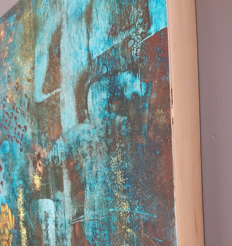 May include: Abstract painting on canvas with a blue, green, and gold color scheme. The painting has a textured surface and is framed in a natural wood frame.