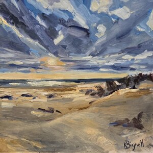 May include: An oil painting on canvas depicting a coastal landscape with sandy dunes in the foreground, a dark blue ocean horizon, and a dramatic sky filled with thick, textured clouds in shades of blue, white, and grey. The artist signature Bignell is visible.