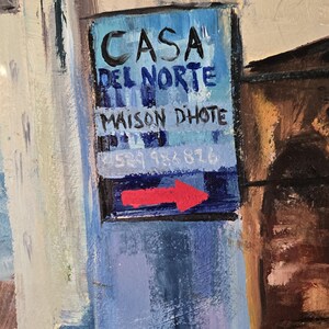 May include: An impressionistic painting of a street scene with a sign that reads "CASA DEL NORTE MAISON DHOTE" with a red arrow. The artwork features buildings in shades of blue, white, and brown.