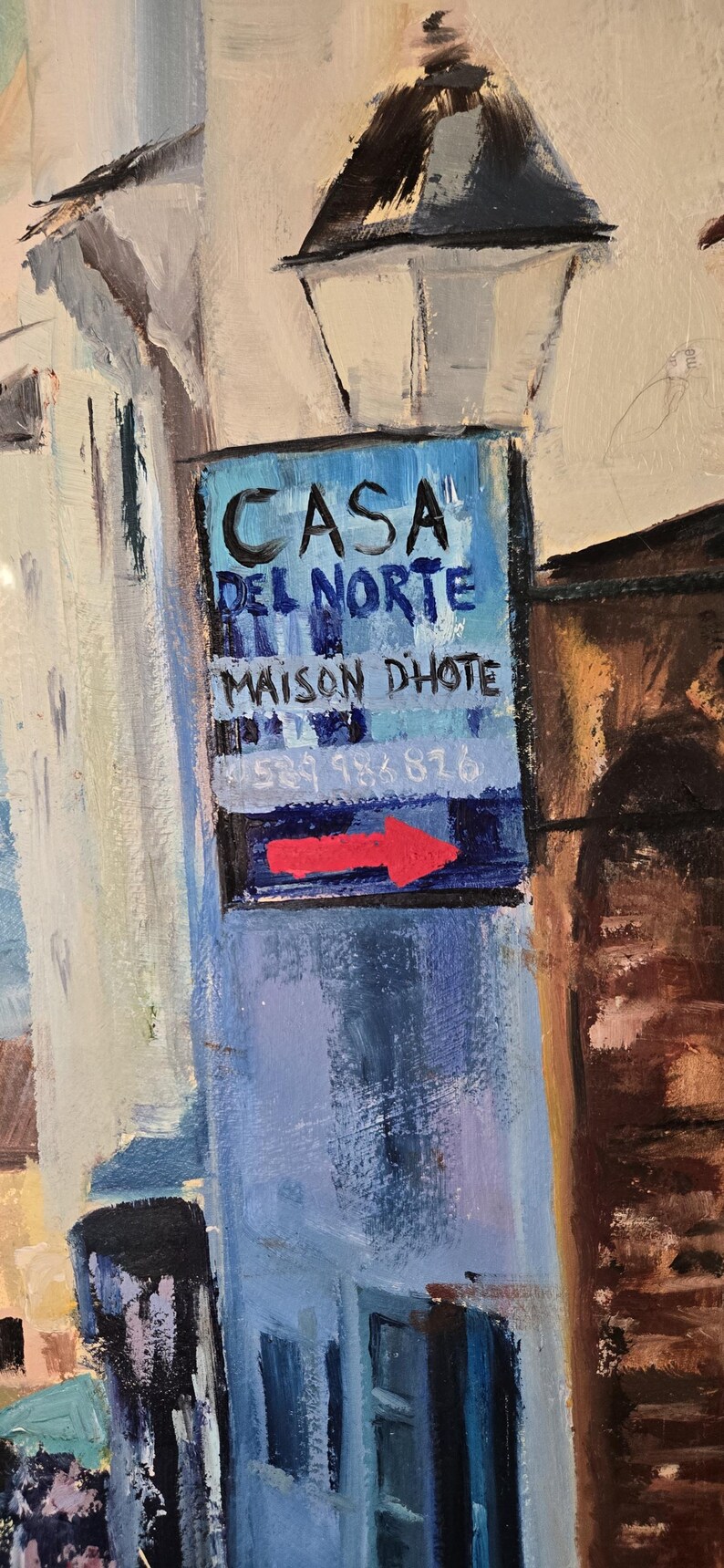 May include: An impressionistic painting of a street scene with a sign that reads "CASA DEL NORTE MAISON DHOTE" with a red arrow. The artwork features buildings in shades of blue, white, and brown.