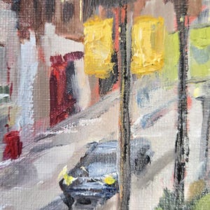 May include: An impressionistic oil painting of a city street scene. The artwork features yellow traffic lights, a car, and buildings with a palette of browns, reds, and grays. The style is loose and textured.