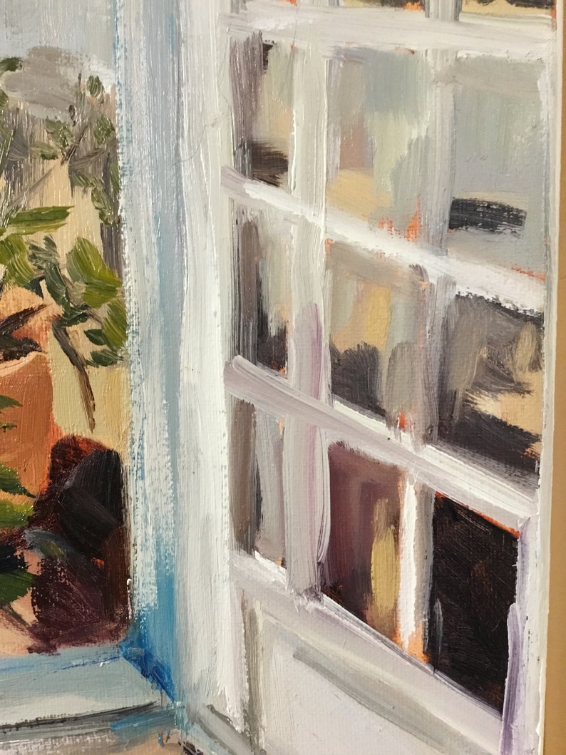 May include: A close-up of a window with white painted trim and a view of a potted plant through the glass. The window is open and the curtains are drawn back.
