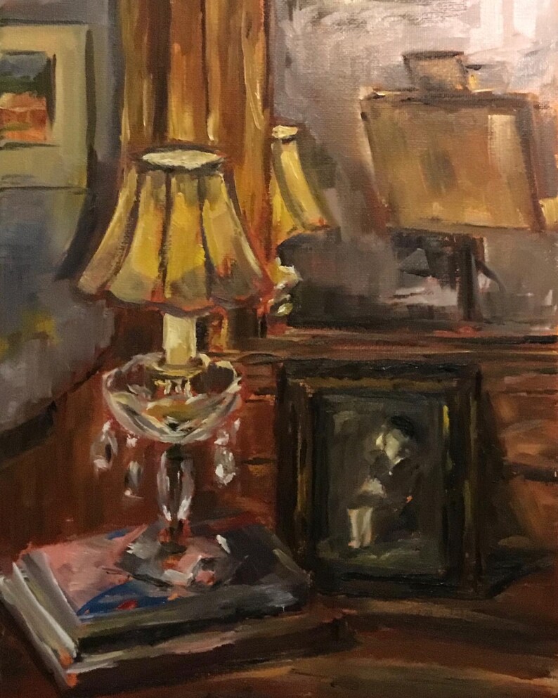 May include: A still life painting of a lamp with a yellow lampshade, a framed picture, and a stack of books on a wooden table.
