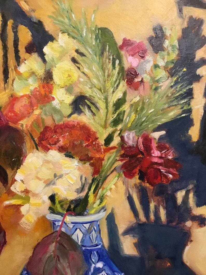 May include: A bouquet of flowers in shades of red, yellow, and green, arranged in a blue and white ceramic vase with a floral pattern. The vase is sitting on a table with a yellow background.