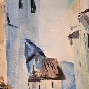 May include: An abstract oil painting depicting a European street scene. The artwork features buildings in shades of white, blue, and brown, with a street lamp and power lines. The brushstrokes are visible, creating a textured effect.