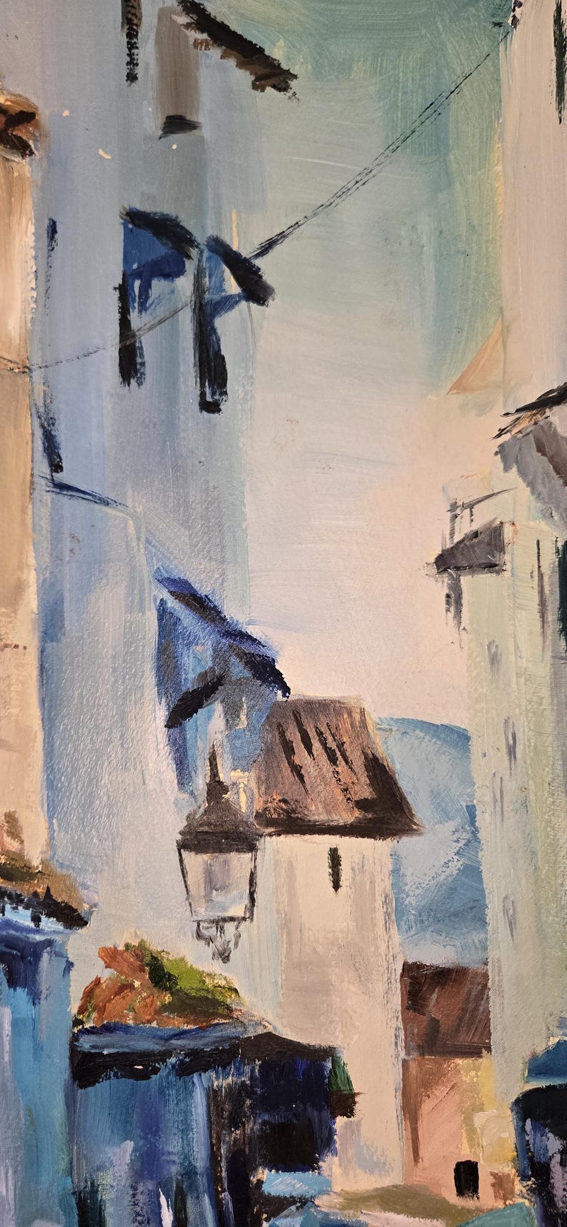 May include: An abstract oil painting depicting a European street scene. The artwork features buildings in shades of white, blue, and brown, with a street lamp and power lines. The brushstrokes are visible, creating a textured effect.