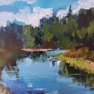 Puede incluir: Una pintura que representa una escena de bosque con un lago azul en primer plano. Los &aacute;rboles son una mezcla de verde y marr&oacute;n, y el cielo es azul claro con nubes blancas. El lago refleja el cielo y los &aacute;rboles.