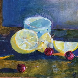 Puede incluir: Pintura al &oacute;leo de un bodeg&oacute;n con una taza azul claro, limones en rodajas y cerezas. Los limones son amarillos y las cerezas son de color rojo intenso. El fondo es una mezcla de azul y marr&oacute;n.