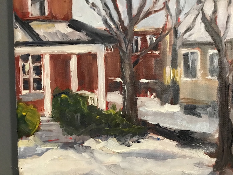 May include: A painting of a red brick house with a white porch and a green bush in front. The house is covered in snow and there are bare trees in the background.