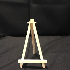 May include: A small wooden easel, perfect for displaying small artwork or photos. The easel is made of natural wood and has a simple, classic design.