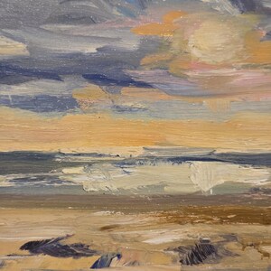 May include: An oil painting on canvas depicting a coastal landscape with thick, visible brushstrokes. The scene features a sandy beach in the foreground, a dark blue ocean with white-capped waves, and a dramatic sky filled with dark blue and orange clouds.