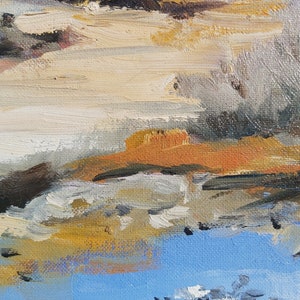 May include: Abstract painting with brushstrokes of white, brown, orange, and blue paint. The painting has a textured surface.